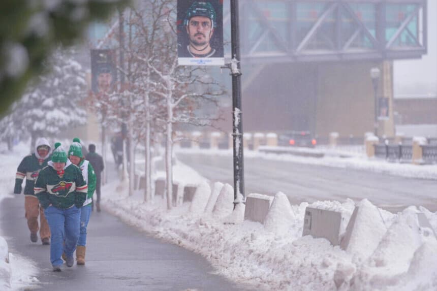 Los aficionados caminan por las calles nevadas antes de un partido de hockey de la NHL entre los Minnesota Wild y los Toronto Maple Leafs, en St. Paul, Minnesota, el 15 de marzo de 2026. (Abbie Parr/AP Photo).