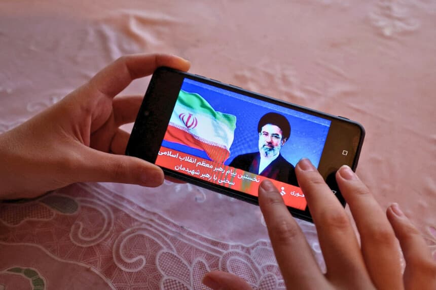 Una niña ve en su teléfono móvil una declaración televisada del nuevo líder de Irán, Mojtaba Jamenei, el 12 de marzo de 2026. (AFP vía Getty Images).