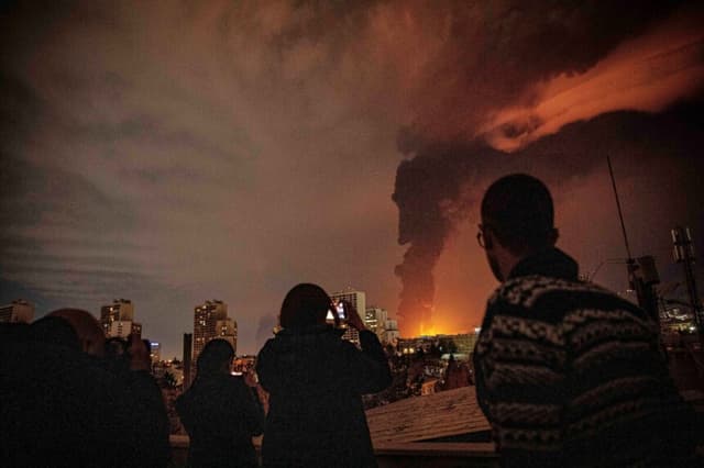 Los residentes observan y toman fotografías mientras las llamas y el humo se elevan desde una instalación de almacenamiento de petróleo alcanzada por los ataques que azotaron la ciudad durante la campaña militar estadounidense-israelí en Teherán, Irán, el 7 de marzo de 2026. (Alireza Sotakbar/ISNA vía AP).