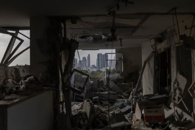 Esta fotografía muestra el interior de un apartamento destruido, con el perfil urbano de Tel Aviv visible al fondo, tras un ataque con misiles iraní perpetrado durante la noche del 19 de marzo de 2026. Según informaron los servicios médicos el 19 de marzo, una serie de disparos de misiles iraníes lanzados durante la noche causó la muerte de un hombre identificado como trabajador extranjero a unos 20 kilómetros al noreste de Tel Aviv. (Foto de Ilia YEFIMOVICH / AFP vía Getty Images).