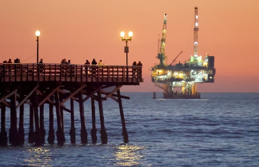 Varias personas se encuentran en un muelle con la plataforma petrolífera y de gas Esther a la distancia en Seal Beach, California, el 5 de enero de 2025. (Mario Tama/Getty Images)