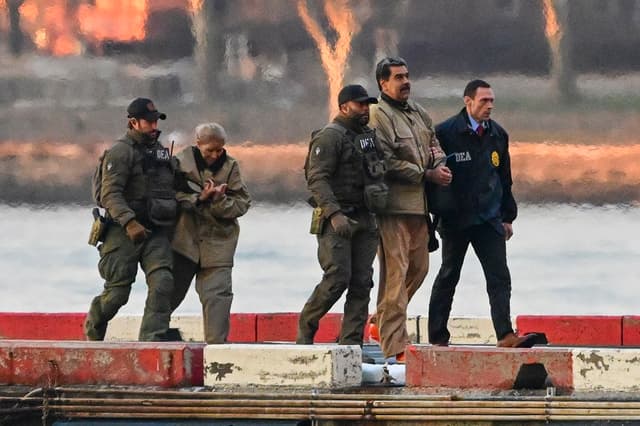 Nicolás Maduro y su esposa, Cilia Flores (Izq.), son escoltados por agentes federales tras aterrizar en un helipuerto de Manhattan, mientras se dirigen a un vehículo blindado en ruta hacia un tribunal federal en la ciudad de Nueva York ,el 5 de enero de 2026. Imagen de archivo. (EFE/EPA/Stringer)