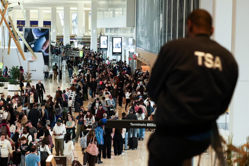 Un agente de la Administración de Seguridad en el Transporte (TSA) observa a los pasajeros que hacen cola para pasar el control de seguridad en el aeropuerto LaGuardia de Nueva York el 22 de marzo de 2026. A partir del 23 de marzo se desplegarán agentes de inmigración en los aeropuertos estadounidenses con el objetivo de aliviar la creciente congestión en los controles de seguridad, en medio de un enfrentamiento presupuestario que dura ya varias semanas y que gira en torno a la campaña de deportaciones masivas del presidente Donald Trump, según informaron las autoridades. Trump anunció esta medida extraordinaria en una publicación en las redes sociales el domingo por la mañana, lo que llevó a las autoridades a ponerse manos a la obra para elaborar rápidamente un plan. (Foto de CHARLY TRIBALLEAU / AFP vía Getty Images).