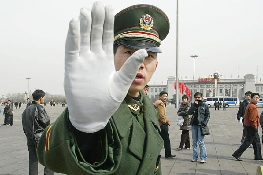 Imagen Ilustrativa: Policía del régimen comunista chino hace un gesto mientras patrulla la Plaza de Tiananmen, 4 de marzo de 2003. (FREDERIC BROWN / AFP vía Getty Images).