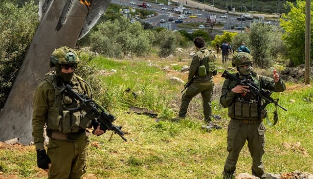 Soldados israelíes junto a un misil iraní incrustado en el suelo el 24 de marzo de 2026 en la aldea palestina de Hares, en Cisjordania. (Erik Marmor/Getty Images)