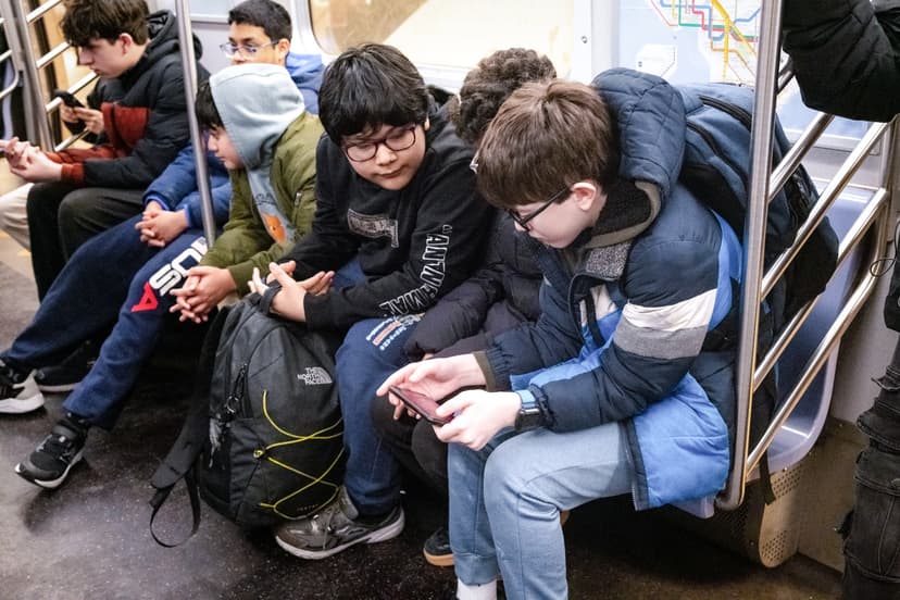 Unos jóvenes miran un teléfono en el metro de la ciudad de Nueva York el 26 de marzo de 2026. (Samira Bouaou/The Epoch Times).