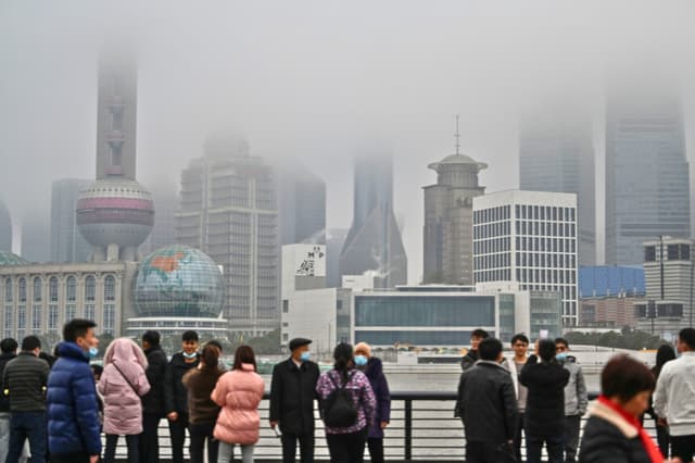 Varias personas pasean por el paseo del Bund, frente al distrito financiero de Lujiazui, a orillas del río Huangpu, en Shanghái, el 7 de marzo de 2021. (Foto de Héctor RETAMAL / AFP) (Foto de HÉCTOR RETAMAL/AFP vía Getty Images).