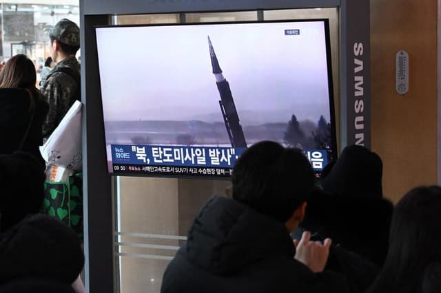 Varias personas se sientan frente a una pantalla de televisión que muestra un noticiero con imágenes de archivo de una prueba de misiles norcoreana, en una estación de tren de Seúl el 4 de enero de 2026. (Jung Yeon-je / AFP vía Getty Images)