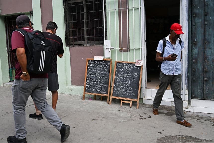Unos hombres observan los carteles de precios de un negocio privado en La Habana, el 16 de marzo de 2026. Los cubanos residentes en el extranjero y sus descendientes podrán invertir y tener sus propios negocios en la isla, según anunció el gobierno comunista el 16 de marzo de 2026, en un momento en que la economía del país se encuentra prácticamente paralizada. (YAMIL LAGE / AFP vía Getty Images)