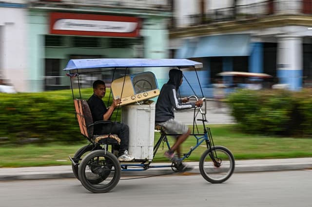 Un hombre transporta lavadoras en un bicitaxi por una calle de La Habana, el 22 de abril de 2026. (YAMIL LAGE / AFP vía Getty Images)