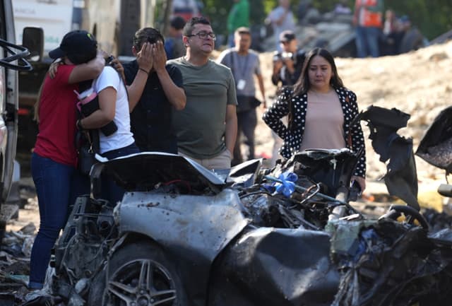 Familiares de las víctimas del atentado ocurrido en la Vía Panamericana lloran este domingo frente a los escombros de los vehículos destruidos, en Cajibío, Colombia. (EFE/Ernesto Guzmán)