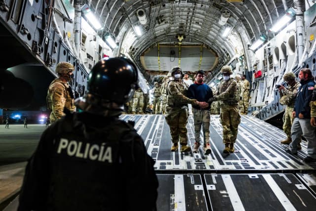 Personal militar estadounidense escolta a presuntos miembros de la pandilla venezolana Tren de Aragua y de la MS-13, recientemente deportados por el gobierno de EE. UU. para ser encarcelados en el Centro de Confinamiento por Terrorismo del Aeropuerto Internacional de El Salvador en San Luis Talpa, El Salvador, el 12 de abril de 2025. (Secretaría de Prensa de la Presidencia/Handout vía Reuters)