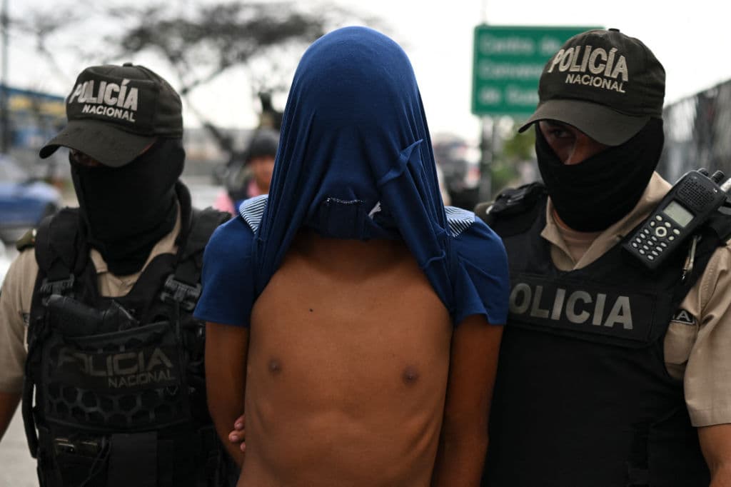 Agentes de la Policía Nacional de Ecuador escoltan a un hombre detenido bajo sospecha de pertenecer a una banda criminal durante un operativo conjunto con miembros de las Fuerzas Armadas en una de las principales avenidas de Guayaquil, Ecuador, el 15 de enero de 2024. Foto de YURI CORTEZ/AFP vía Getty Images