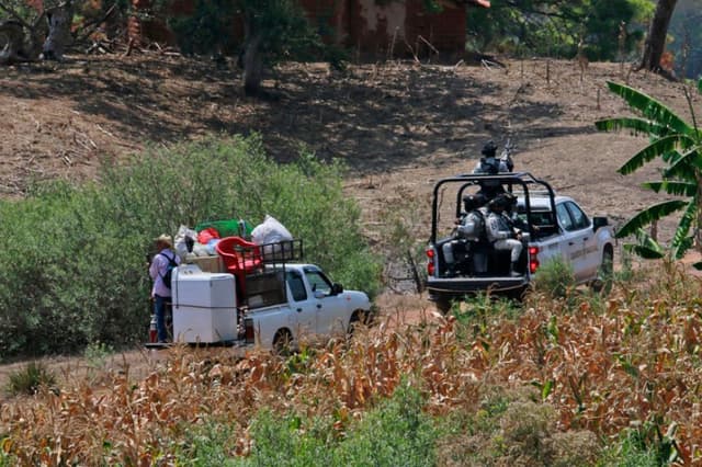Pobladores son resguardados por integrantes de la Guardia Nacional de México el 18 de mayo, en la zona donde se suscitaron enfrentamientos el pasado 11 de mayo en Chilapa, Guerrero, México. Una semana después del desplazamiento de comunidades indígenas por los ataques armados de grupos del crimen organizado, varias comunidades de Chilapa de Álvarez, Guerrero, lucen abandonadas por el temor de sus habitantes a una nueva ola de violencia a su regreso. (EFE/José Luis De La Cruz)