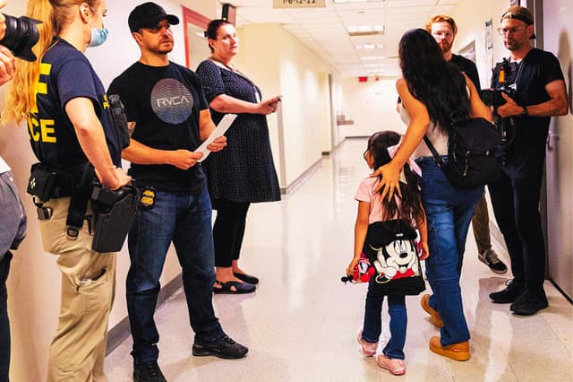 Una mujer y un niño pasan junto a agentes federales mientras estos patrullan los pasillos del tribunal de inmigración en el Edificio Federal Jacob K. Javits el 28 de julio de 2025 en la ciudad de Nueva York. (Michael M. Santiago/Getty Images)