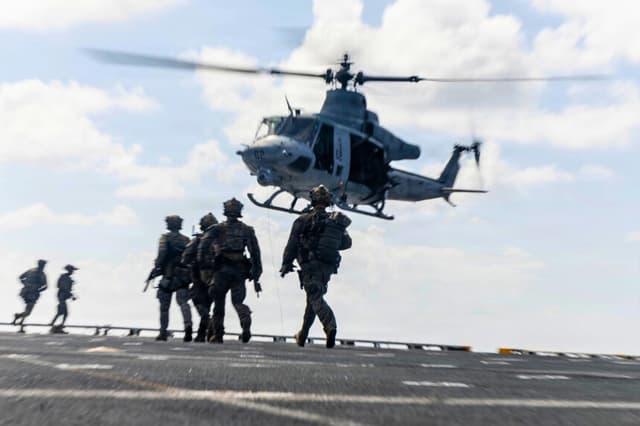 Marines estadounidenses adscritos a la Fuerza de Combate Litoral 24 se acercan a un helicóptero UH-1Y Venom durante un simulacro de interceptación marítima a bordo del USS Fort Lauderdale, mientras navegan por el mar Caribe, el 22 de mayo de 2026. (Cuerpo de Marines de Estados Unidos).