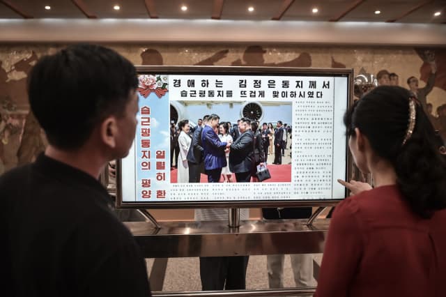 La gente mira una pantalla con el periódico "Rodongsinmun" que muestra la noticia sobre la visita del presidente de China, Xi Jinping, en la estación Kaeson del metro de Pyongyang, el 9 de junio de 2026. (Kim Won Jin / AFP vía Getty Images)