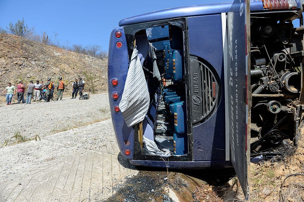 Varias personas permanecen cerca de un autobús volcado, el 10 de febrero de 2016. Imagen de Archivo (FEDERICO PARRA/AFP vía Getty Images)