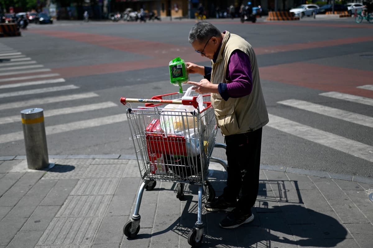 Un hombre revisa los productos comprados en un carrito frente a un supermercado en Beijing el 11 de mayo de 2026. (Wang Zhao / AFP vía Getty Images).