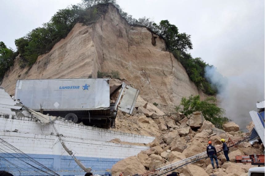 Integrantes del Cuerpo de Bomberos de Honduras atienden el derrumbe de un cerro sobre una bodega este martes, en Tegucigalpa, Honduras. (EFE/ STR)