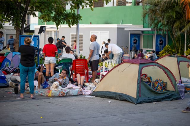 Recostados en colchones, sábanas, sillas, carpas y campamentos improvisados, cientos de personas duermen en el asfalto, jardineras, plazas y canchas en Catia La Mar, una de las ciudades más afectadas por los terremotos de magnitud 7.2 y 7.5 ocurridos el miércoles en Venezuela y que se han cobrado la vida de 235 personas. (EFE/ Ronald Peña R)
