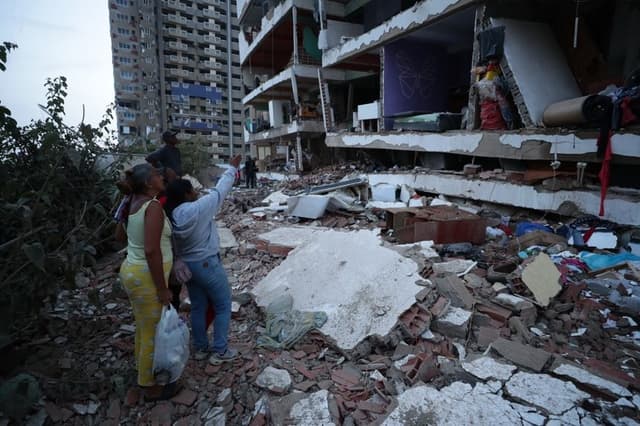 Residentes entre los escombros de uno de los bloques de viviendas dañados por los terremotos, en la localidad de Catia La Mar, en el estado costero de La Guaira, Venezuela, este jueves. (EFE/ Ronald Pena R.)