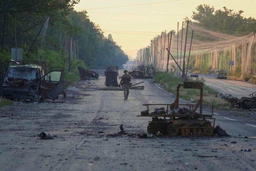Un militar de la brigada consolidada 'Khyzhak' del Departamento de Policía de Patrulla Ucraniana camina por una carretera cerca de redes antidrones y vehículos militares destruidos mientras participa en una misión para proteger una carretera de drones rusos entre las ciudades del frente de Druzhkivka y Kostiantynivka, en la región de Donetsk, Ucrania, el 24 de junio de 2026. (Anatolii Stepanov/Reuters).