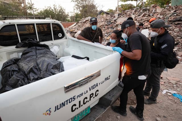Funcionarios del Cuerpo de Investigaciones Científicas, Penales y Criminalísticas (Cicpc), trasladan cuerpos este lunes, en La Guaira, Venezuela. (EFE/ Ronald Peña R)