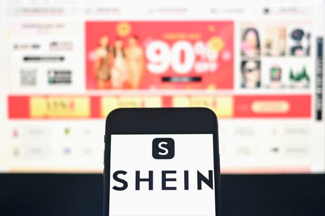 El logotipo de la empresa de comercio electrónico de moda Shein aparece en un teléfono inteligente con la página web de la empresa como fondo, en una fotografía tomada en Bangkok el 6 de diciembre de 2024. (Manan Vatsyayana/AFP vía Getty Images).