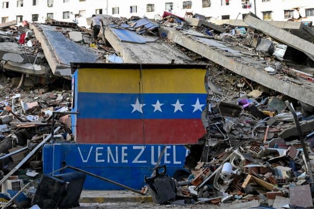 Una bandera venezolana pintada en una pared dañada entre los escombros de un edificio derrumbado tras los terremotos ocurridos en Caraballeda, estado de La Guaira, Venezuela, el 26 de junio de 2026. (Maryorin Méndez / AFP vía Getty Images)
