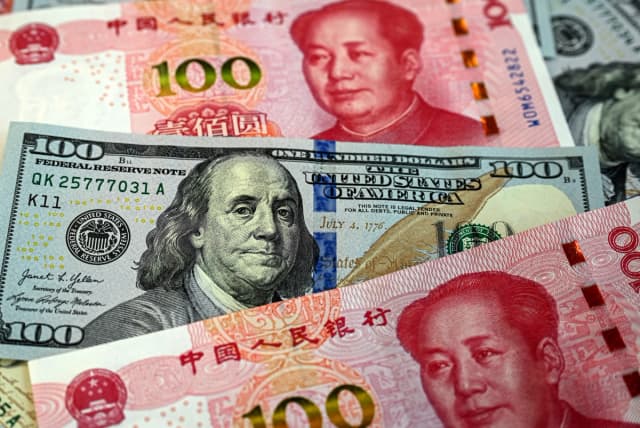 Esta foto ilustrativa muestra billetes chinos de 100 yuanes (rojos) y billetes de 100 dólares estadounidenses en Beijing, el 8 de abril de 2025. (Jade Gao /AFP vía Getty Images).