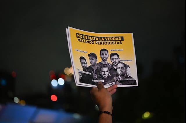 Una mujer sostiene un cartel con fotos en memoria de los periodistas asesinados en la Franja de Gaza, mientras participa en una vigilia en la Ciudad de México el 12 de agosto de 2025. (YURI CORTEZ/AFP vía Getty Images)