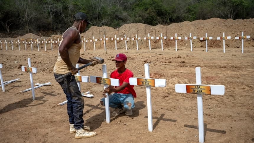 Unos trabajadores clavan una cruz de madera en una fosa recién cavada y marcada con un número en el cementerio La Esperanza, en Catia La Mar, La Guaira, al noreste de Caracas, el 5 de julio de 2026. (Miguel Medina/AFP)