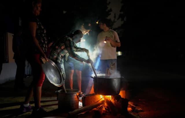 Residentes preparan una sopa sobre una hoguera durante un apagón provocado por el fallo de una importante central eléctrica en La Habana, Cuba, el 19 de octubre de 2024. (Ramon Espinosa/AP).