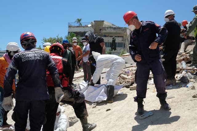 Bomberos y voluntarios rescatan un cuerpo sin vida durante los trabajos de remoción de escombros de los edificios Mision Vivienda OPPE luego del doble terremoto de magnitud 7.2 y 7.5 ocurrido el pasado 24 de Junio, este martes en La Guaira, Venezuela. (EFE/ Xaume Olleros)