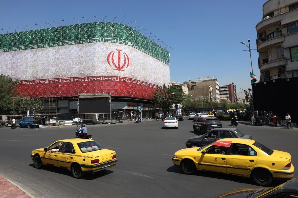 El tráfico pasa junto a la bandera nacional iraní exhibida en un edificio de la plaza Enghelab, en Teherán, el 14 de junio de 2026. (AFP vía Getty Images)