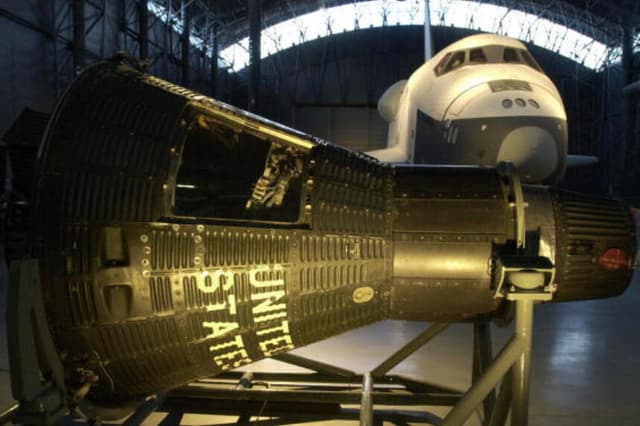 El transbordador espacial Enterprise (al fondo) y la cápsula Mercury 15B "Freedom 7" (al frente) se exhiben en el Museo Nacional del Aire y el Espacio, Centro Steven F. Udvar-Hazy, en Chantilly, Virginia, el 11 de diciembre de 2003. (Joyce Naltchayan/AFP vía Getty Images).