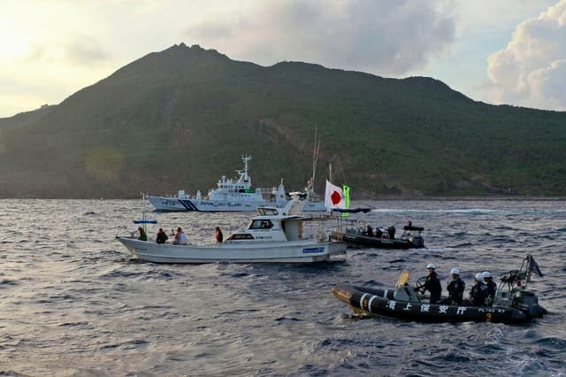 Un buque guardacostas japonés y otras embarcaciones (atrás y a la derecha) navegan junto a un barco pesquero de activistas japoneses (en el centro) cerca de un grupo de islas en disputa, llamadas Diaoyu por China y Senkaku por Japón, el 18 de agosto de 2013. (Foto de Emily Wang/AP).