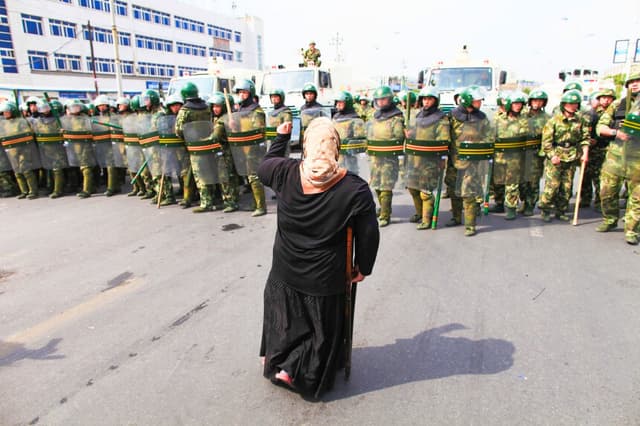Una mujer uigur protesta frente a la policía en una calle de Urumqi, la capital de Xinjiang, el 7 de julio de 2009. (Guang Niu/Getty Images).