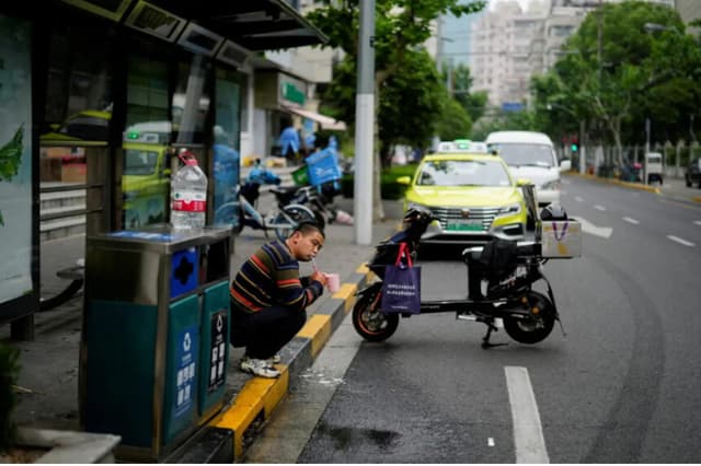 Un domiciliario se cepilla los dientes en una calle de Shanghái el 12 de mayo de 2022. (Aly Song/Reuters).