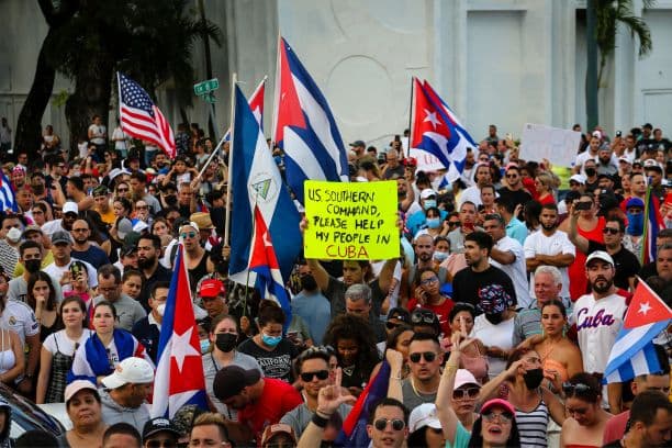La gente se manifiesta, algunos con banderas nacionales de Cuba y Estados Unidos y pancartas, durante una protesta contra el gobierno cubano en Miami el 11 de julio de 2021. Miles de cubanos en todo el país participaron en protestas sin precedentes el 11 de julio de 2021 contra el régimen comunista. (EVA MARIE UZCATEGUI/AFP vía Getty Images)