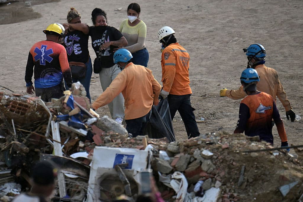 Los familiares reaccionan mientras los equipos de rescate transportan una bolsa para cadáveres La Guaira, Venezuela, el 12 de julio de 2026. (Juan BARRETO / AFP vía Getty Images)
