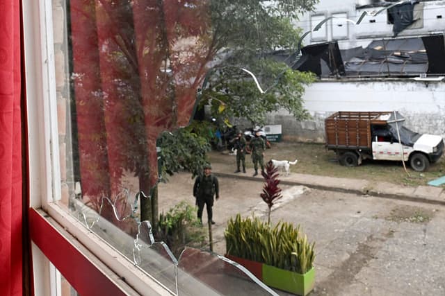 Soldados colombianos observan una ventana destrozada en Suárez, en el departamento del Cauca (Colombia), el 27 de mayo de 2026. (Joaquín SARMIENTO / AFP vía Getty Images)