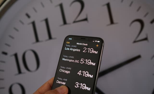 Un reloj detrás de un teléfono inteligente que muestra la hora tras la implementación del horario de verano en Los Ángeles el 15 de marzo de 2022. (Chris Delmas/AFP vía Getty Images)
