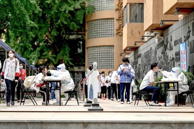 El personal sanitario toma muestras con hisopos a estudiantes para realizarles pruebas de COVID-19 en Beijing el 7 de junio de 2022. (Jade Gao/AFP vía Getty Images)