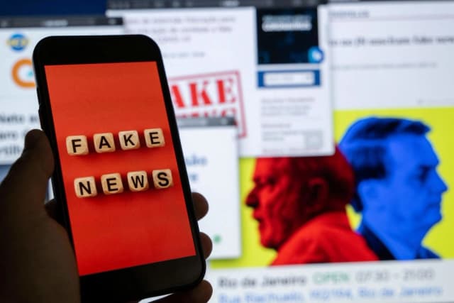 Una ilustración muestra la pantalla de un teléfono inteligente con la frase "Noticias falsas" frente a la pantalla de una computadora de escritorio que muestra varios informes de noticias e investigaciones sobre noticias falsas y desinformación relacionadas con las próximas elecciones presidenciales brasileñas, en Río de Janeiro, Brasil, el 29 de agosto de 2022. (Mauro Pimentel/AFP vía Getty Images).