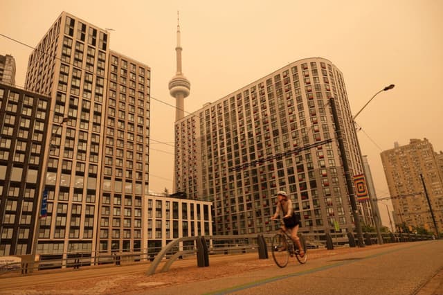 Una mujer recorre el paseo marítimo en Toronto mientras el humo de los incendios forestales llena la ciudad, el 15 de julio de 2026. (The Canadian Press/Laura Proctor).