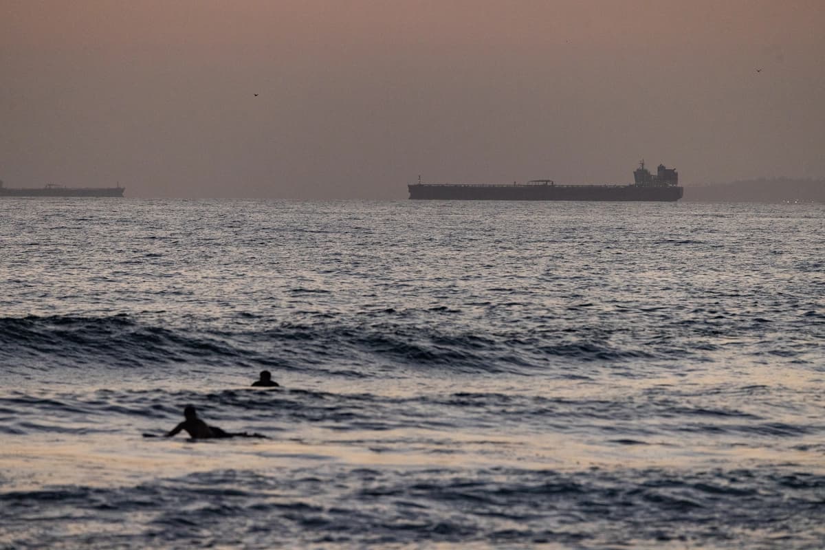 Los bañistas disfrutan del mar con un petrolero de fondo en Huntington Beach, California, el 12 de septiembre de 2024. (John Fredricks/The Epoch Times)