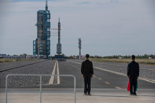 Unos trabajadores se encuentran cerca de la nave espacial tripulada Shenzhou-12, de la Agencia Espacial Tripulada de China, a bordo del cohete Long March-2F antes de su lanzamiento con tres astronautas chinos a bordo en el Centro de Lanzamiento de Satélites de Jiuquan, en la provincia de Gansu, China, el 17 de junio de 2021. (Kevin Frayer/Getty Images)