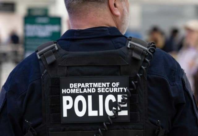 Un oficial del Departamento de Seguridad Nacional da instrucciones a los pasajeros mientras esperan en fila en el Aeropuerto Intercontinental George Bush en Houston, Texas, el 25 de marzo de 2026. (Antranik Tavitian/Reuters)